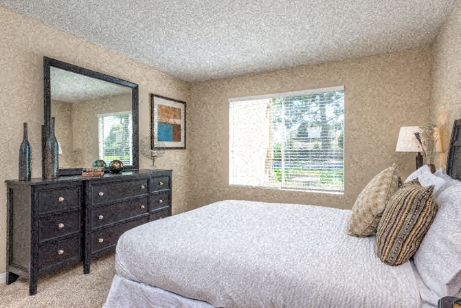 a bedroom with a bed and a dresser and a mirror