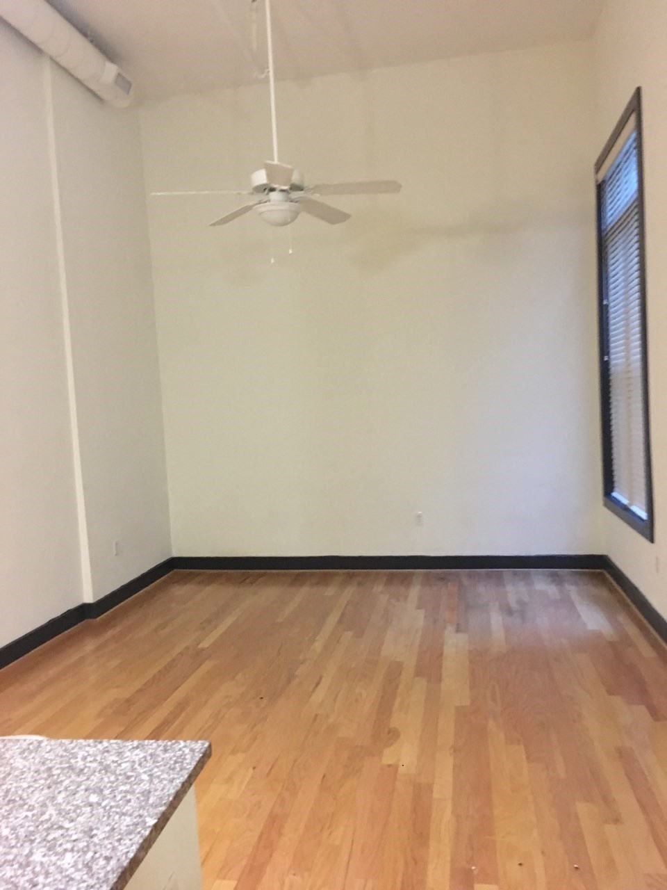 an empty living room with wood floors and a ceiling fan