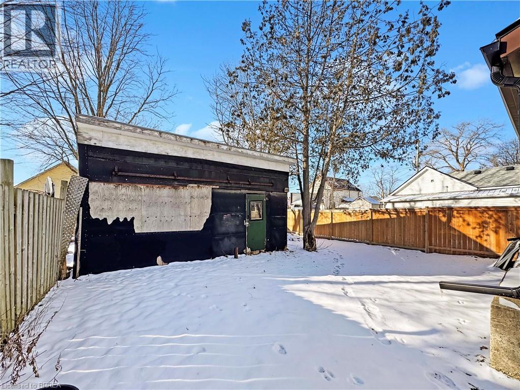A snow-covered ground with a building and trees in the background.