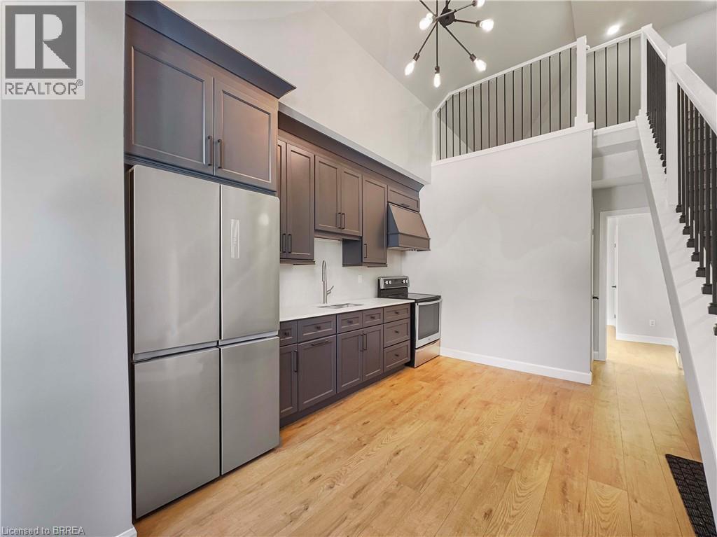 A kitchen with wooden floors and a stainless steel refrigerator.
