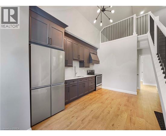 A kitchen with wooden floors and a stainless steel refrigerator.