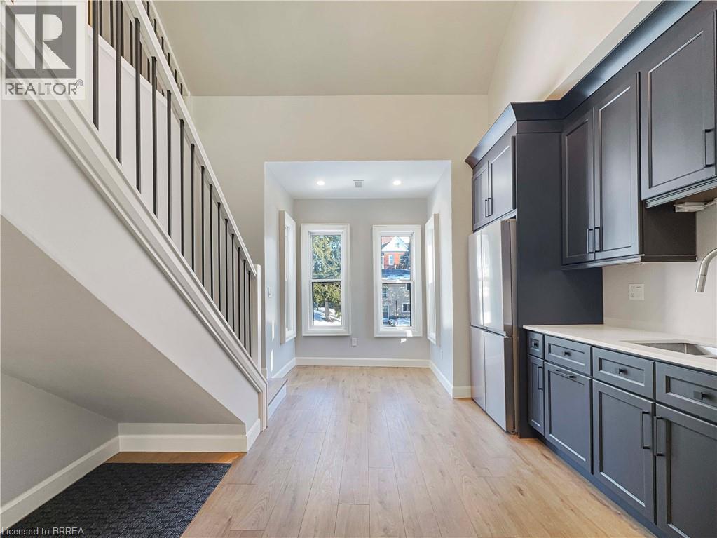 A spacious hallway with wooden floors and a staircase with white railings.