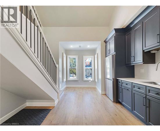 A spacious hallway with wooden floors and a staircase with white railings.