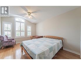 A bedroom with a bed, chair, and window.