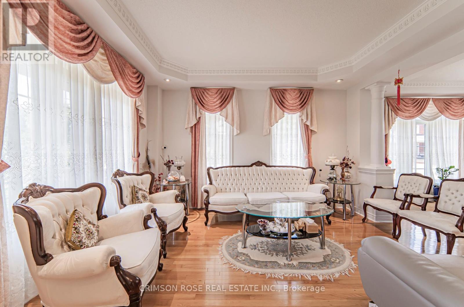 A living room with white furniture and pink drapery.