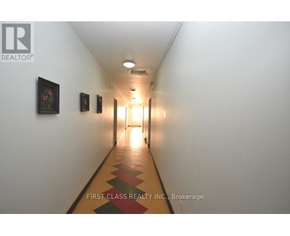 A long hallway with pictures on the wall and a light at the end.