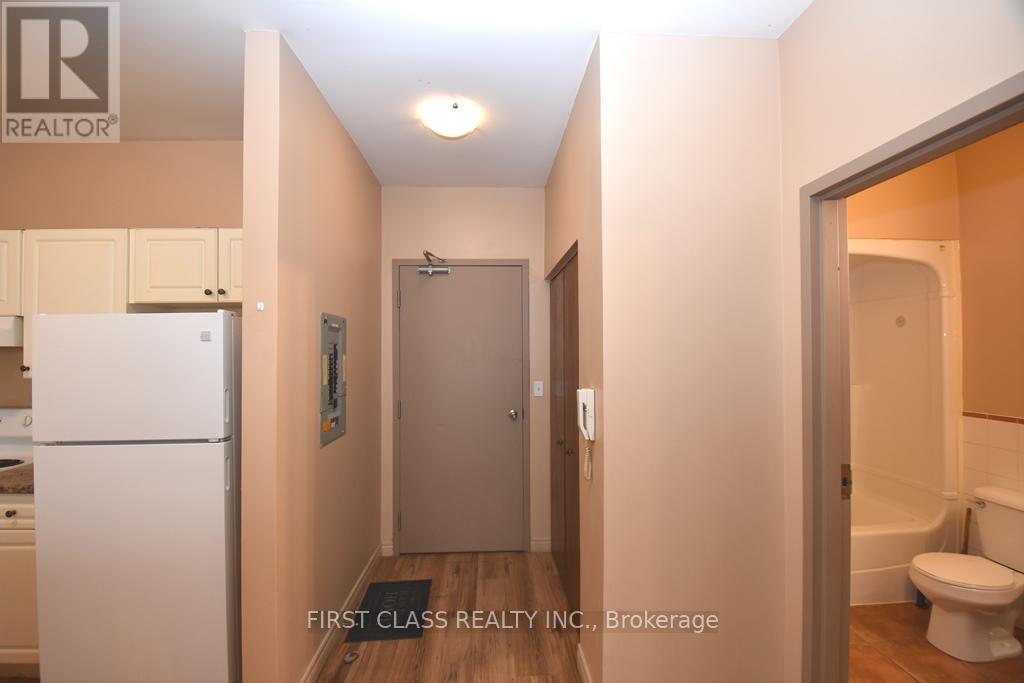 A hallway with a toilet and a sink visible through the door.