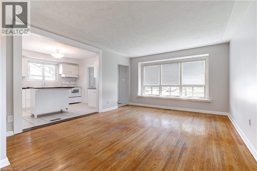 A spacious room with wooden flooring and a large window.