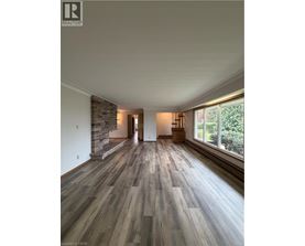 A spacious room with wooden flooring and a stone wall.
