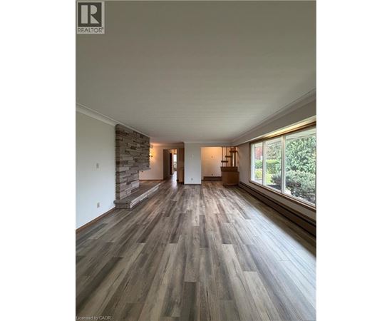A spacious room with wooden flooring and a stone wall.