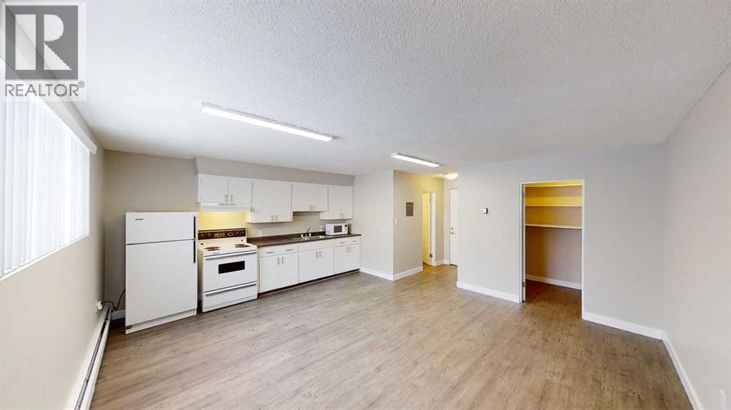 A well-lit, spacious kitchen with white appliances and wooden flooring.