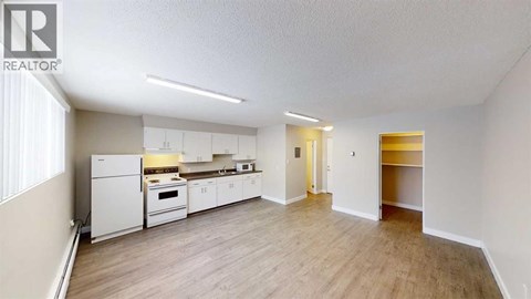 A well-lit, spacious kitchen with white appliances and wooden flooring.