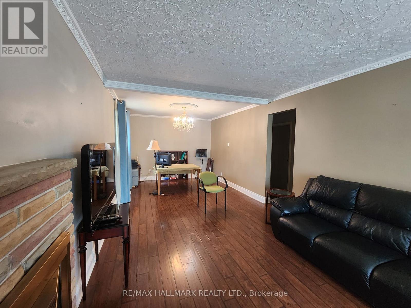 A living room with a black leather couch and a wooden floor.