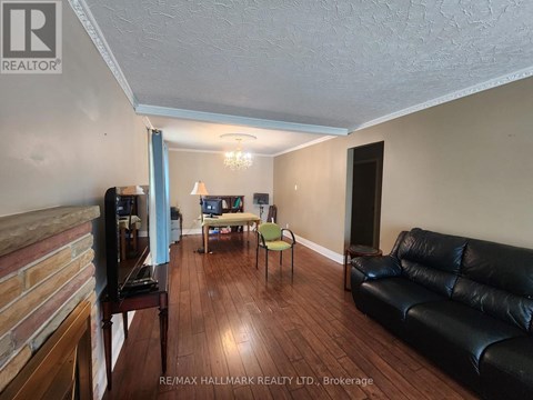 A living room with a black leather couch and a wooden floor.