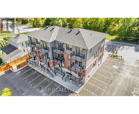 An aerial view of a multi-story apartment building with a parking lot in front.