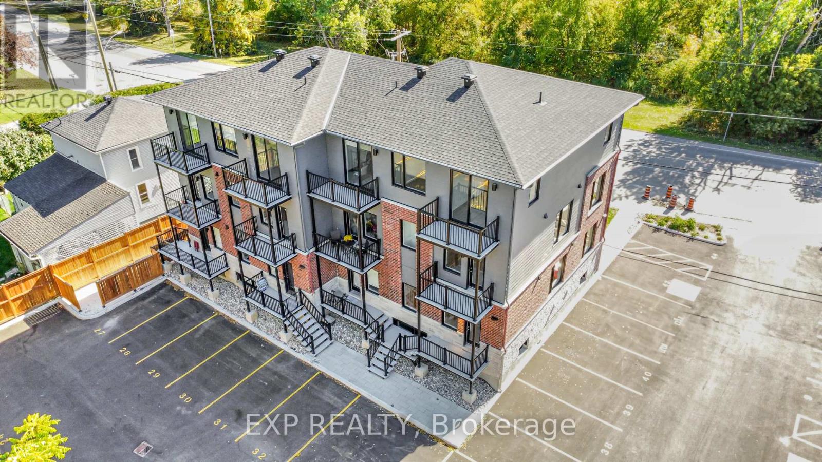 An aerial view of a multi-story apartment building with a parking lot in front.