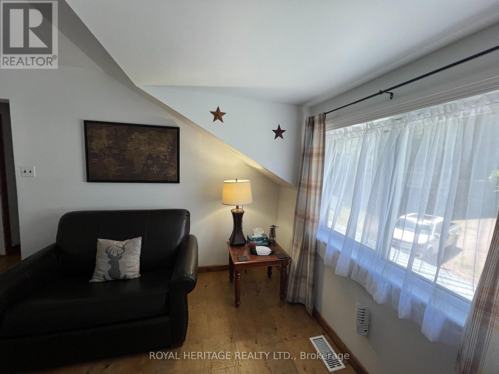 A living room with a black couch, a lamp, and a painting on the wall.