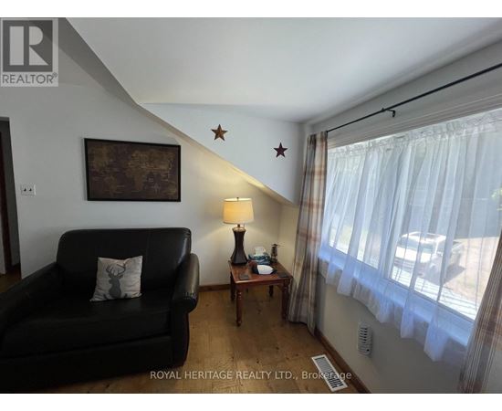 A living room with a black couch, a lamp, and a painting on the wall.