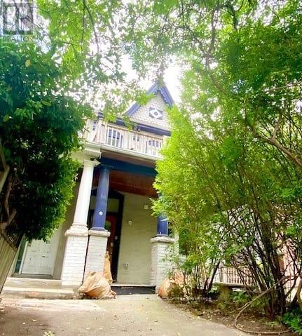 A house with a blue roof and white columns is surrounded by trees.