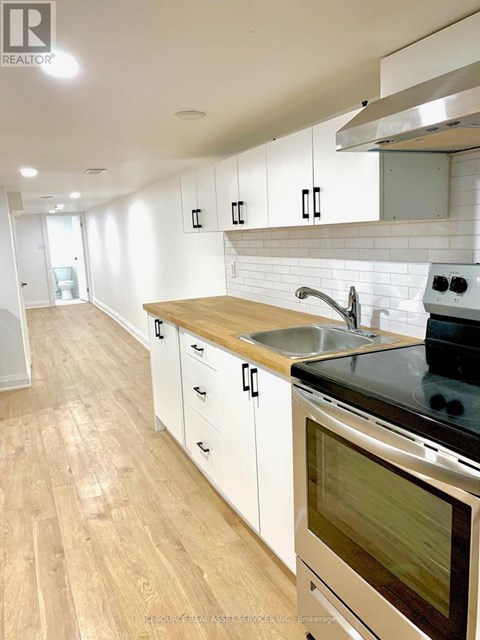 A modern kitchen with white cabinets and a wooden countertop.