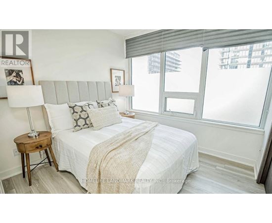 A bedroom with a large bed and a window with blinds.