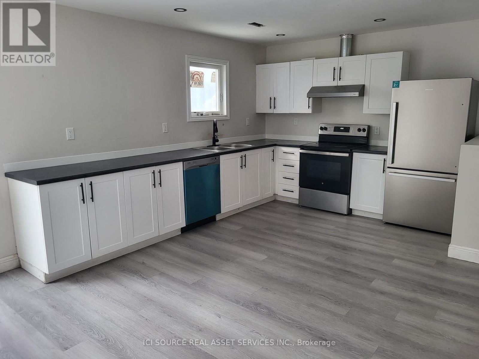 A kitchen with white cabinets and a grey floor.