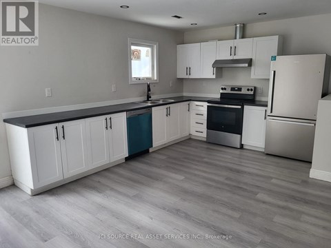 A kitchen with white cabinets and a grey floor.