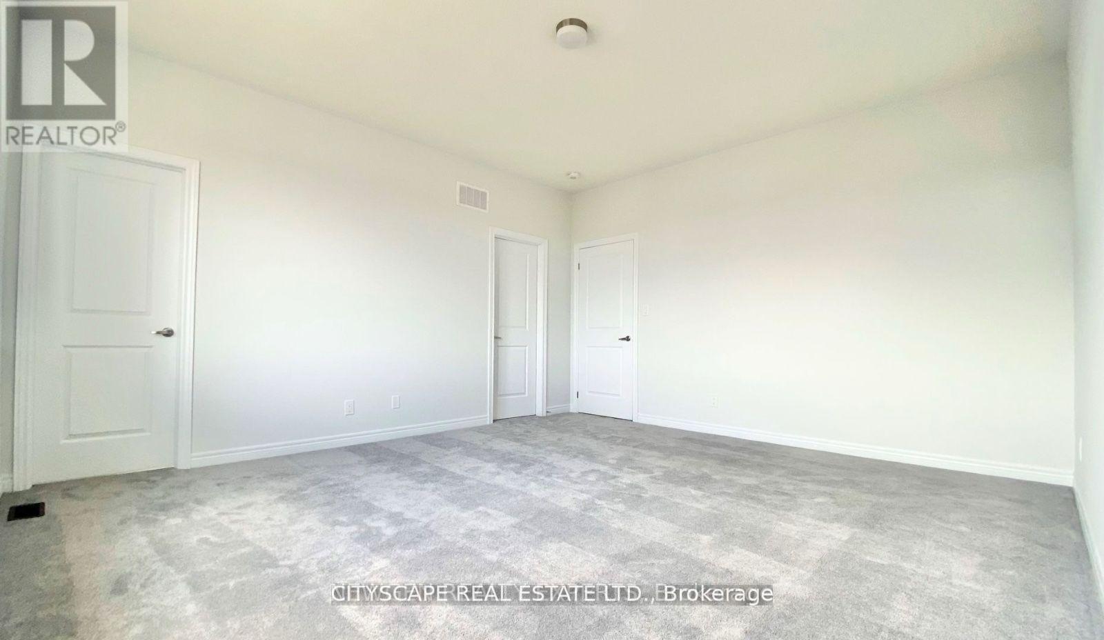 A room with two doors and a brokerage sign on the wall.