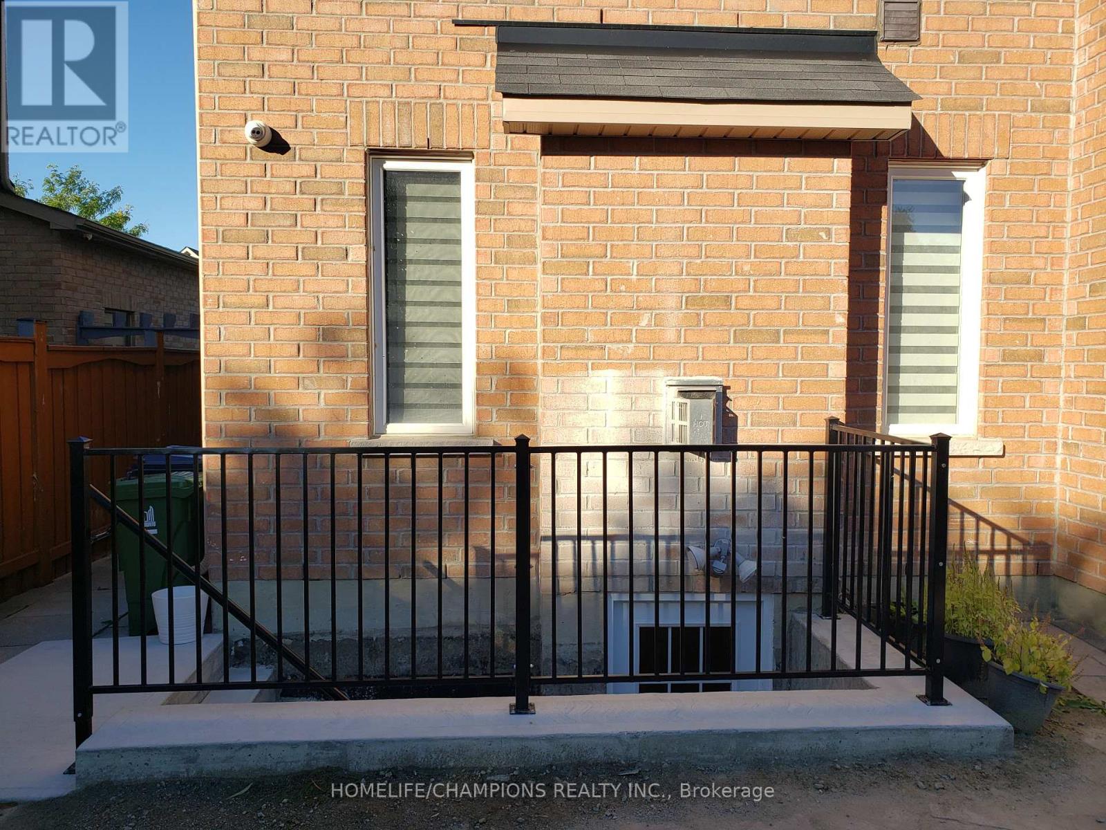 A brick house with a black fence and a small garden.