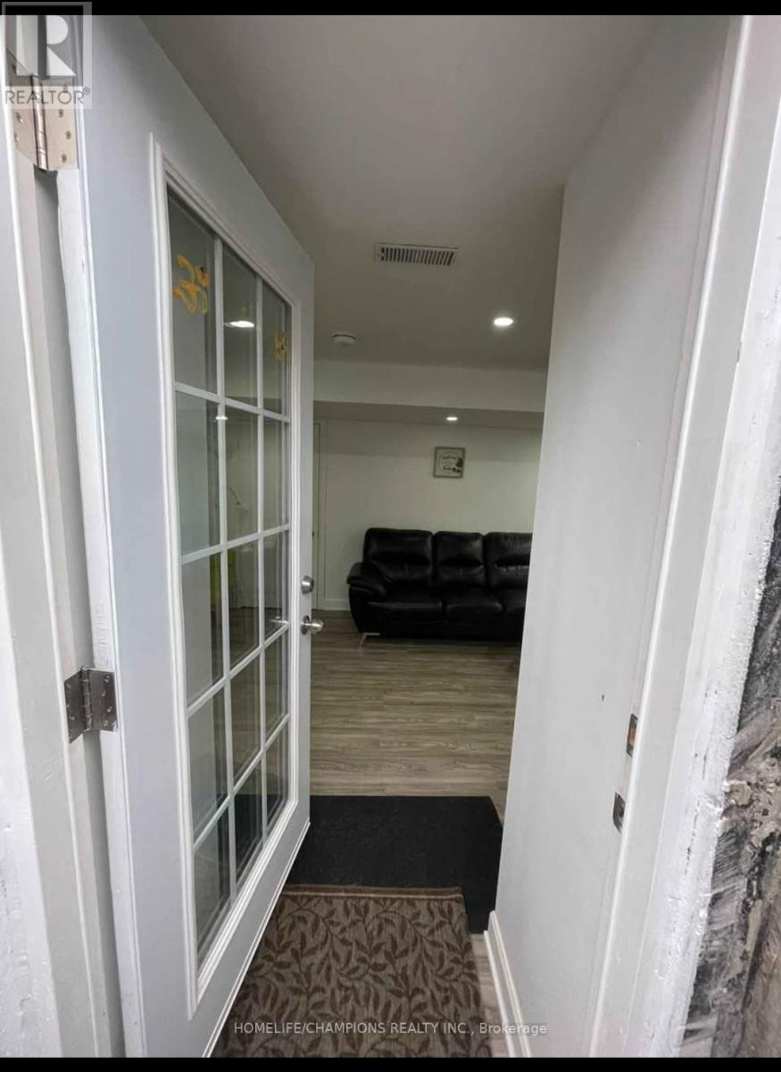 A hallway with a door and a couch in the background.