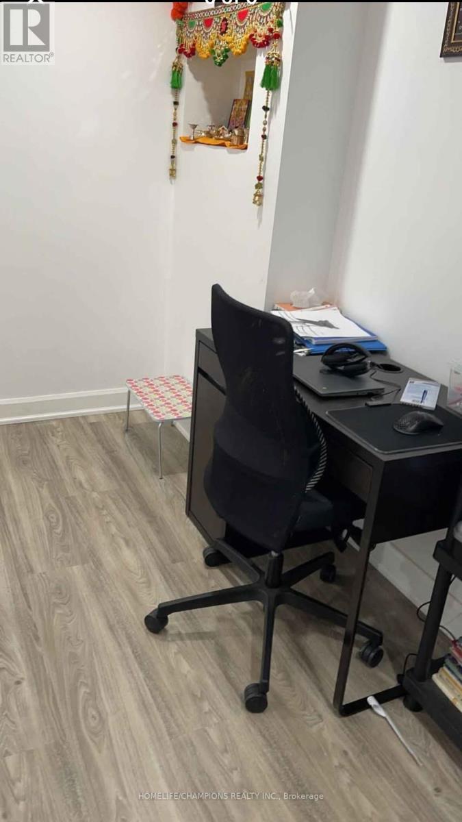 A black office chair is positioned in front of a desk with a computer and mouse.