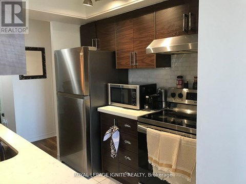 A kitchen with a refrigerator, microwave, oven, and stove.