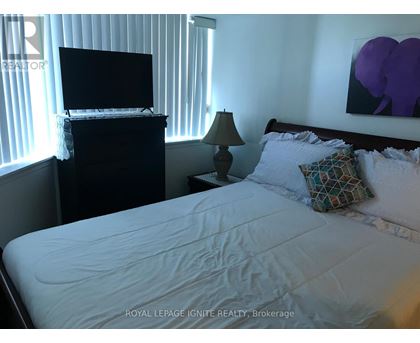 A bedroom with a bed, a television, and a lamp.
