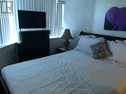 A bedroom with a bed, a television, and a lamp.