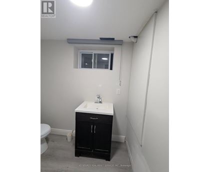 A bathroom with a sink, toilet, and cabinet.
