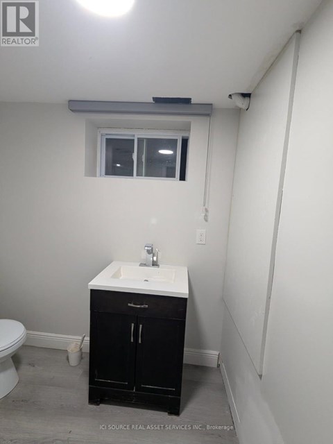 A bathroom with a sink, toilet, and cabinet.