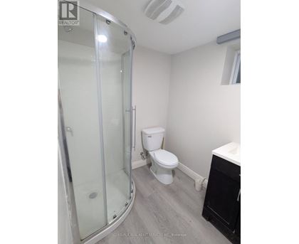 A white toilet sits in a bathroom next to a glass shower stall.