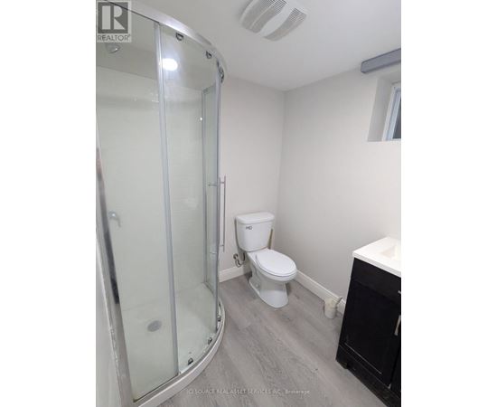 A white toilet sits in a bathroom next to a glass shower stall.