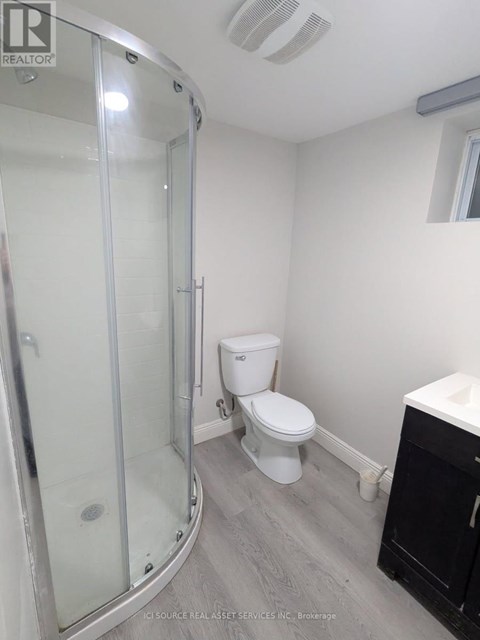 A white toilet sits in a bathroom next to a glass shower stall.