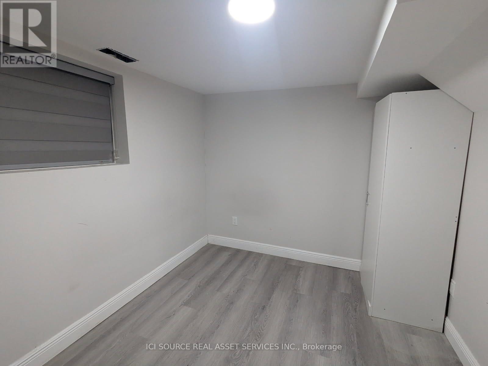 A room with a grey floor and a window with blinds.