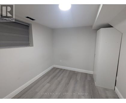 A room with a grey floor and a window with blinds.