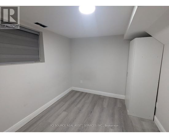 A room with a grey floor and a window with blinds.
