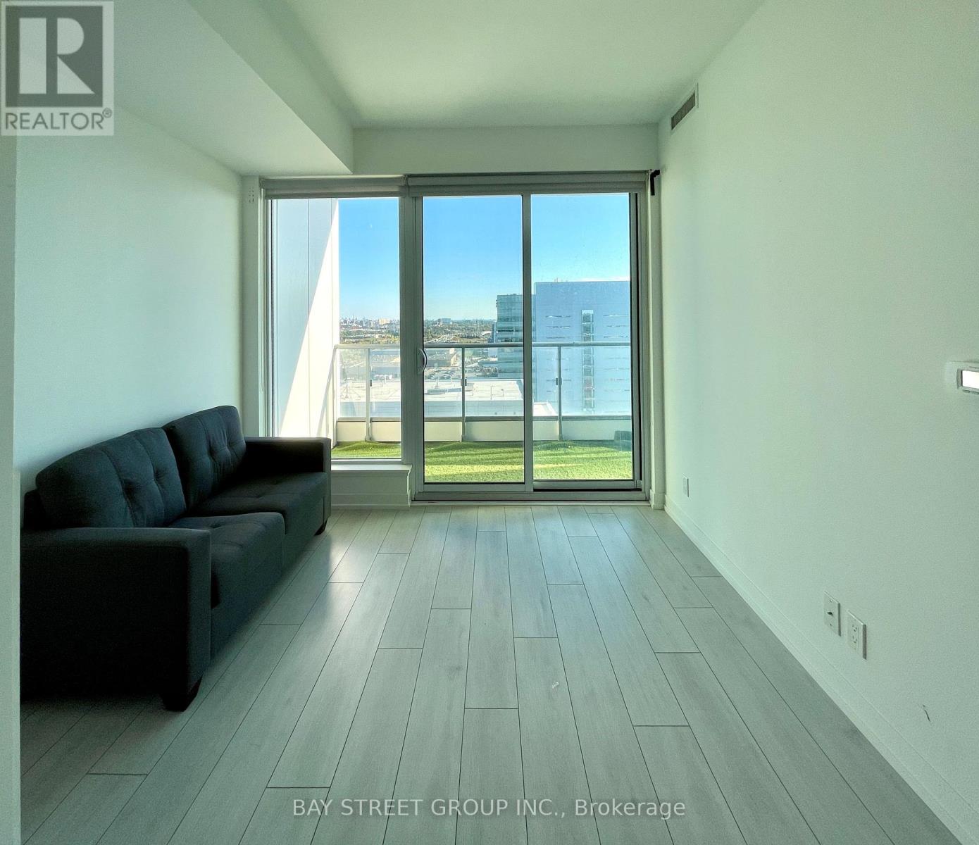 A living room with a couch and a view of the city through the window.