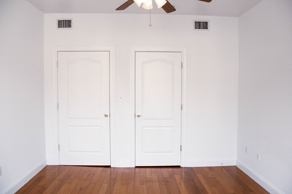 an empty room with two white doors and a ceiling fan