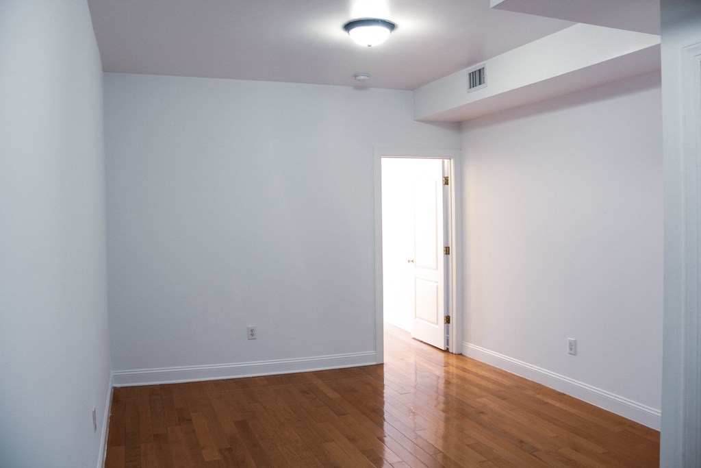 an empty living room with white walls and wood floors
