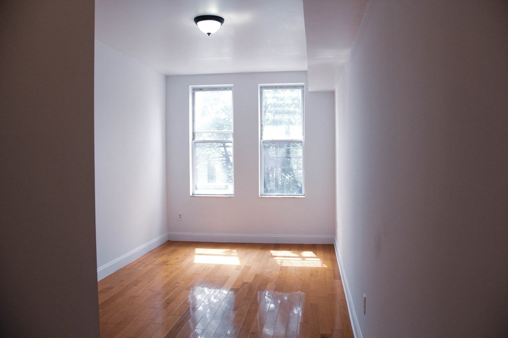 an empty room with two windows and a hard wood floor
