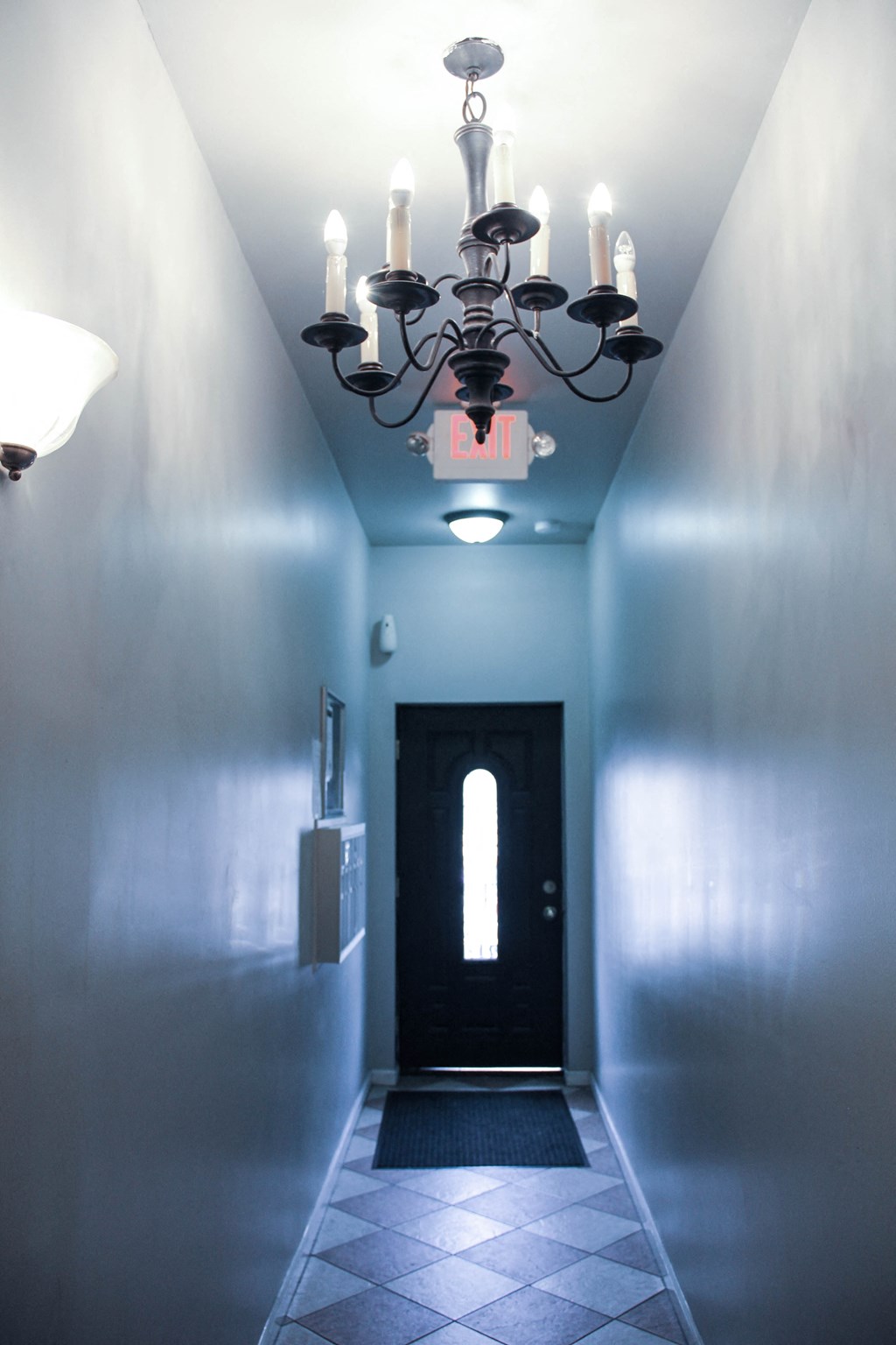 a hallway with a chandelier and a black door