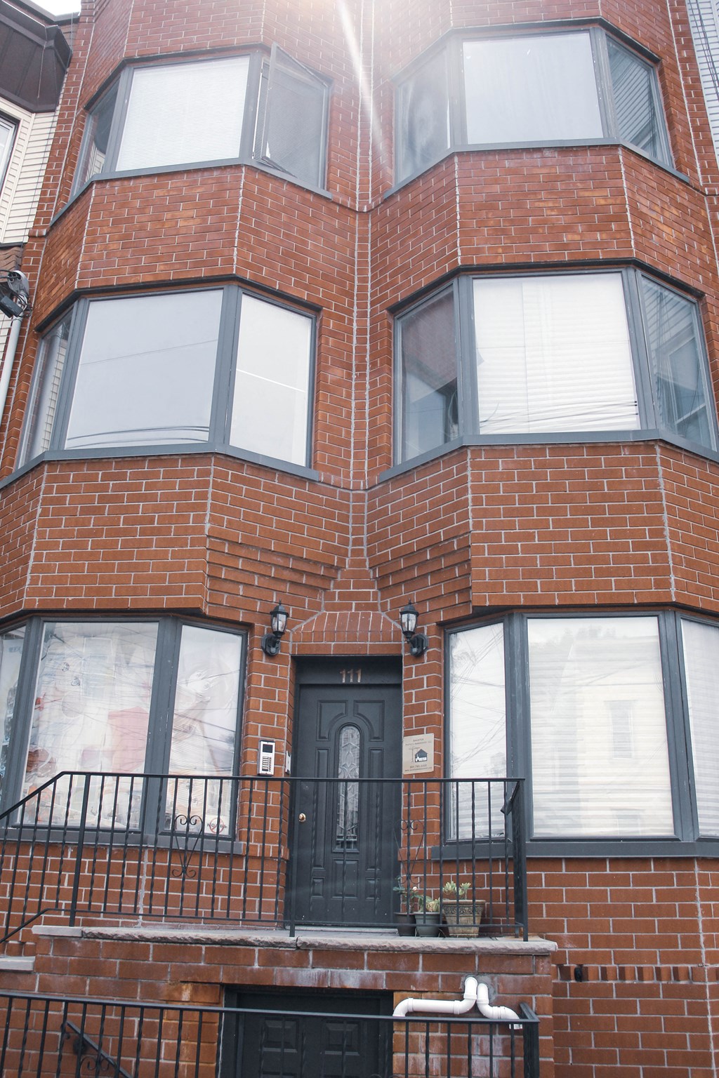 the front of a brick building with a black door and balcony