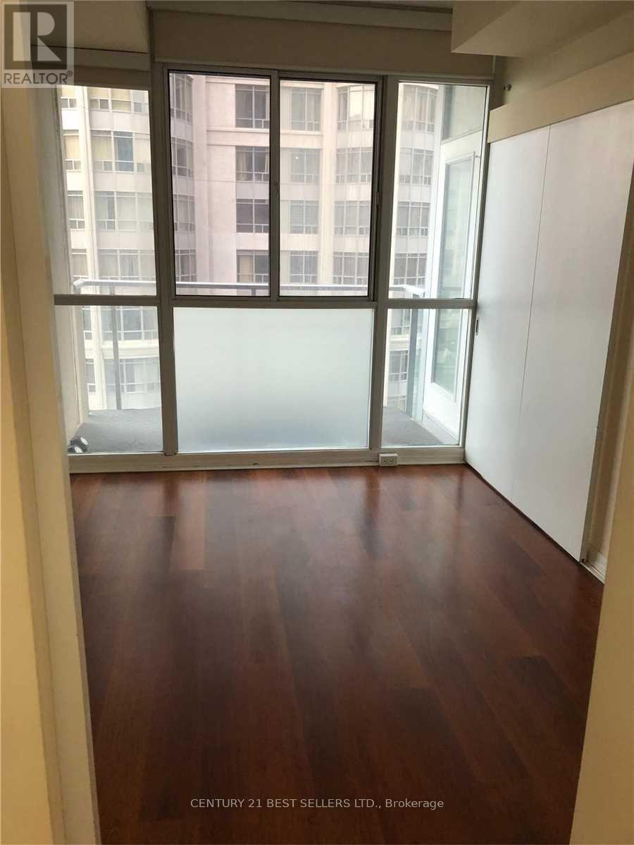 A room with a wooden floor and a glass door leading to a balcony.