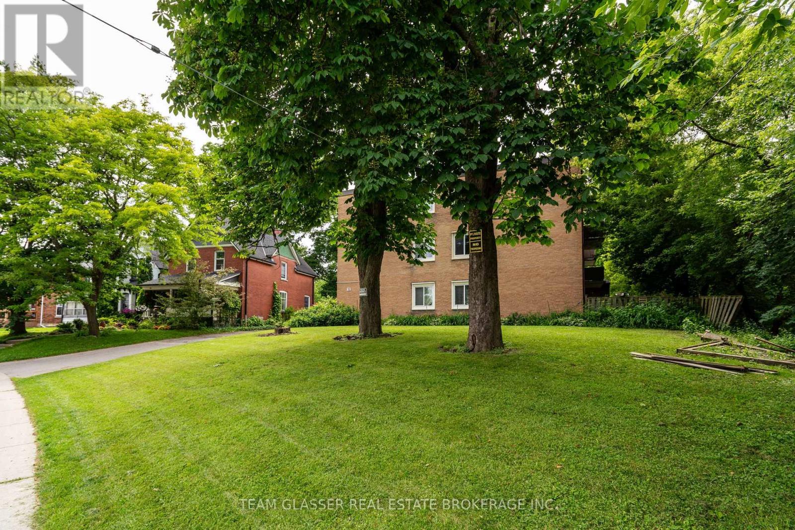 A tree in a yard with a house in the background.
